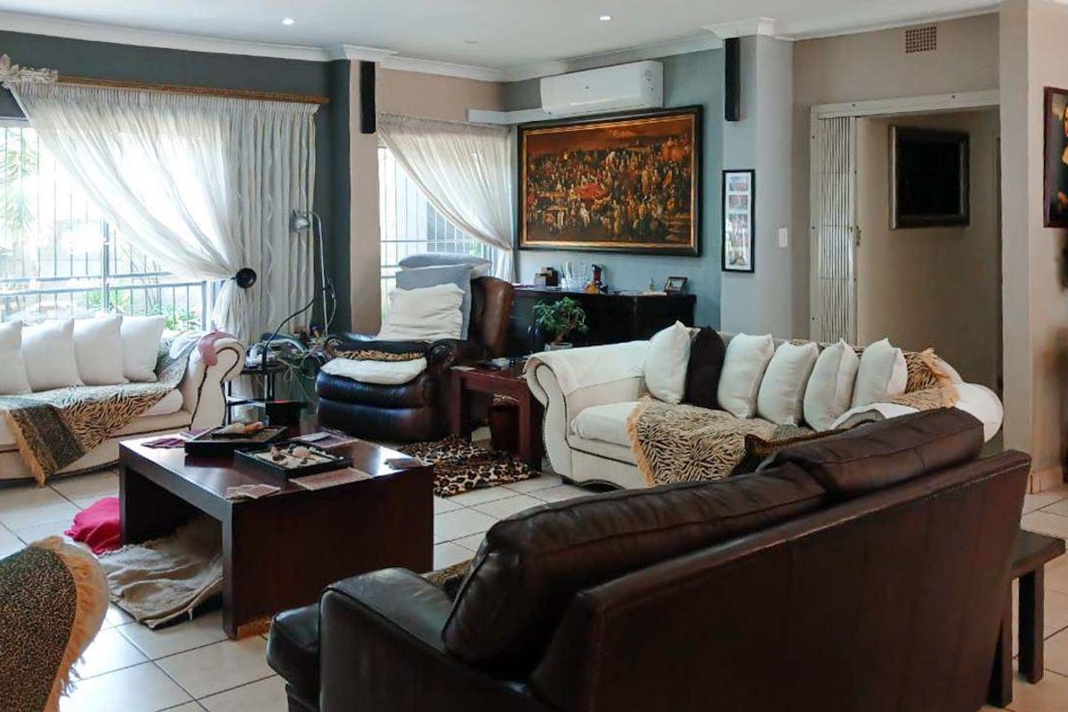 Spacious living room featuring tiled flooring, recessed downlighting, and a wall-mounted split-system air conditioner, with large sliding glass doors providing natural light.