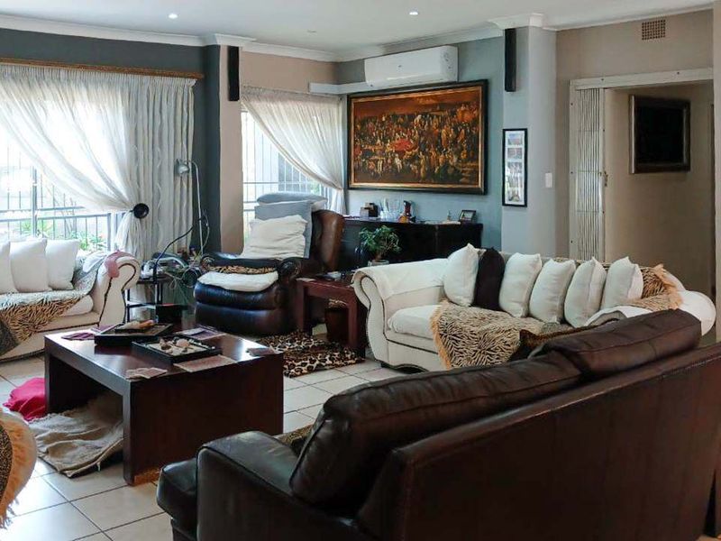 Spacious living room featuring tiled flooring, recessed downlighting, and a wall-mounted split-system air conditioner, with large sliding glass doors providing natural light.