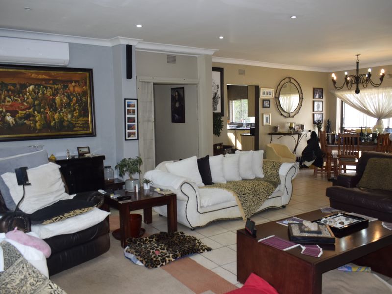 Spacious open-plan living and dining area featuring tiled flooring, recessed lighting, and a wall-mounted air conditioning unit.