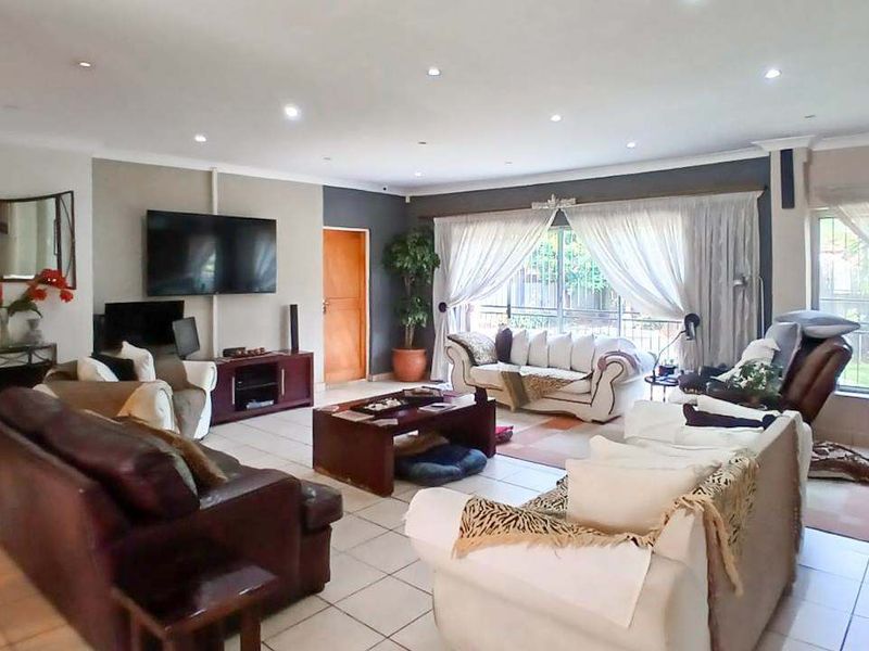 Spacious living room featuring tiled flooring, recessed downlighting, and large sliding glass doors providing natural light and garden access.