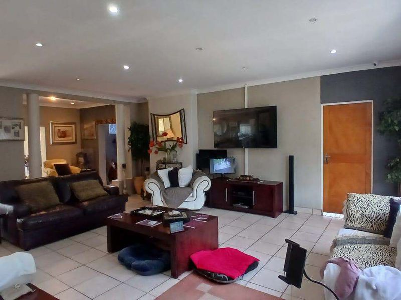 Spacious open-plan living area featuring neutral wall tones, ceramic tiled flooring, and recessed downlighting with access to outdoor space via sliding glass doors.