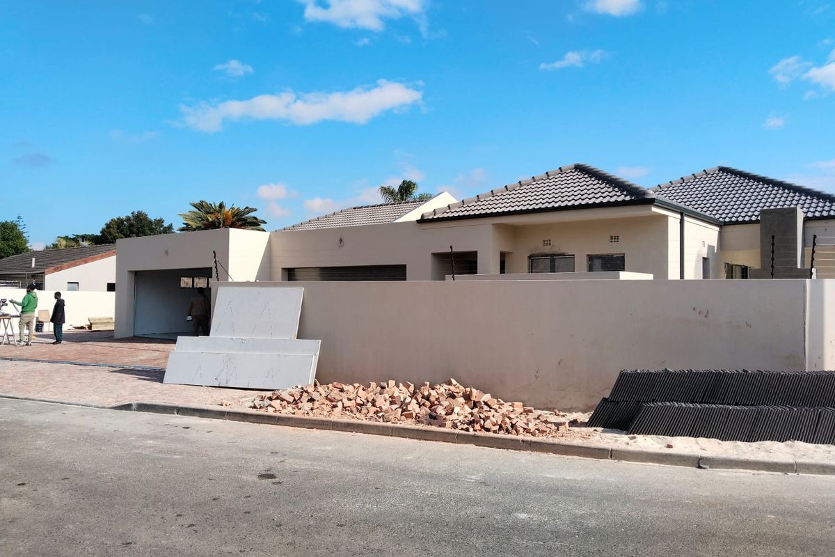 Front exterior view of a townhouse featuring a tiled roof, boundary wall, and garage, currently undergoing final construction or renovation work.