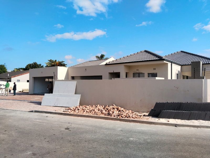 Front exterior view of a townhouse featuring a tiled roof, boundary wall, and garage, currently undergoing final construction or renovation work.