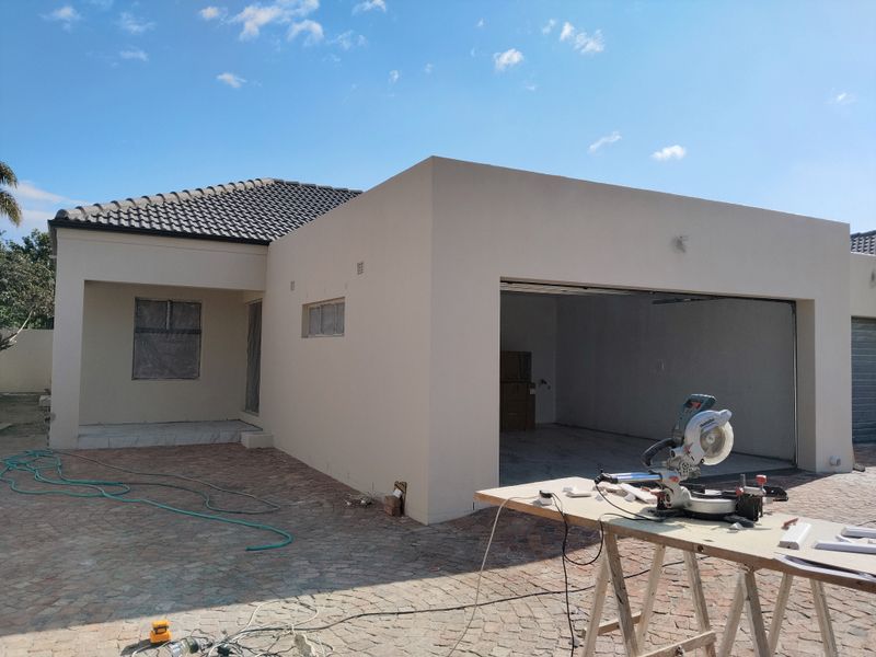 Front exterior view of a townhouse featuring a double garage, paved driveway, and tiled roof, currently undergoing minor construction or finishing works.