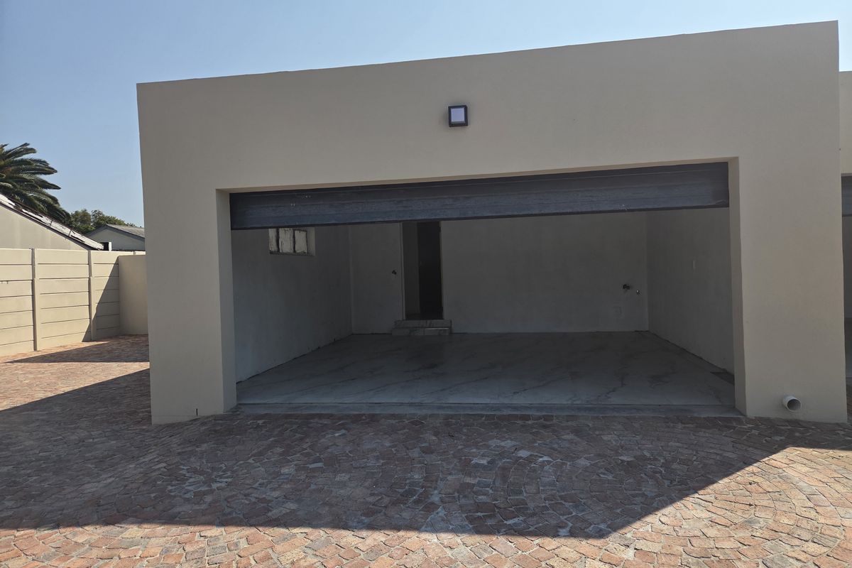 A detached garage structure featuring a paved driveway and open entrance, providing secure parking space.