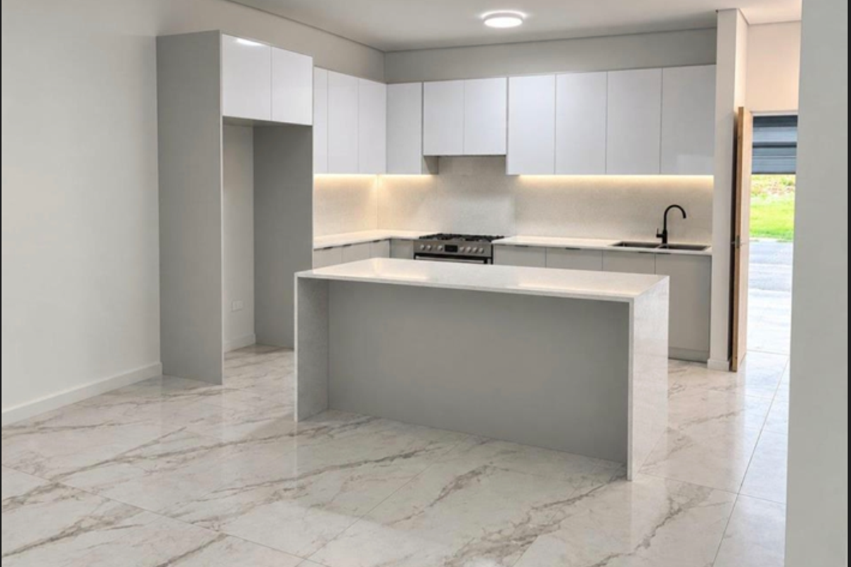 Modern kitchen featuring sleek white cabinetry, stone countertops, a central island, and high-quality marble-look porcelain floor tiles.