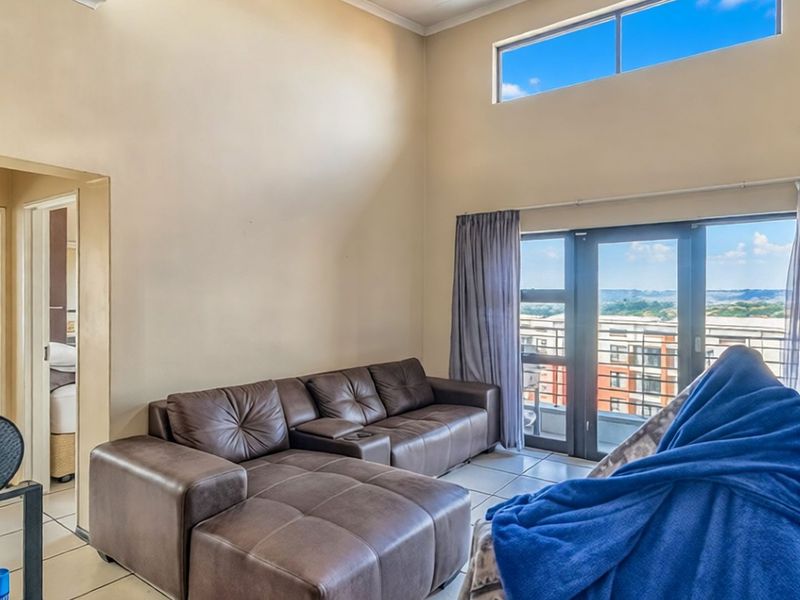 Spacious living area featuring high ceilings, clerestory windows for natural light, and direct access to a balcony with exterior views.