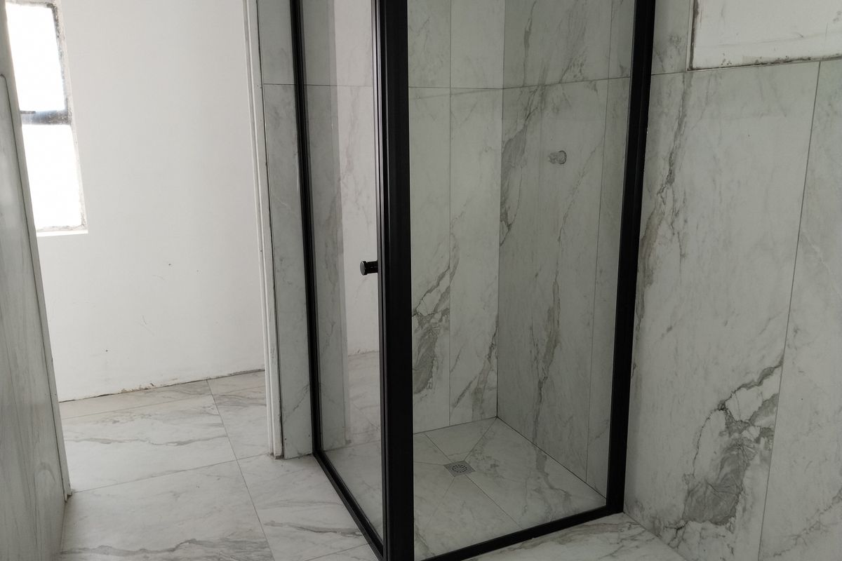 Modern bathroom featuring a walk-in shower with a sleek black frame and contemporary marble-look wall and floor tiling.