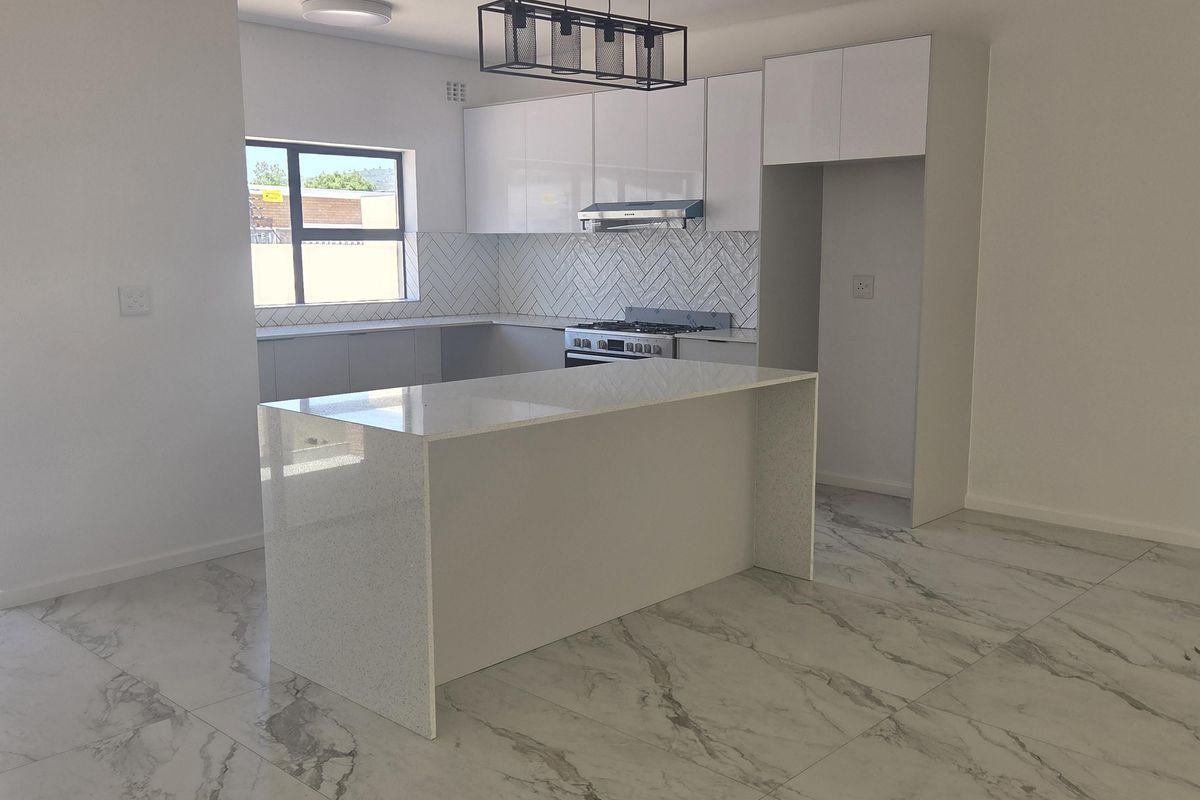 Modern, bright kitchen featuring a central island, quartz countertops, herringbone backsplash, and high-quality marble-look floor tiles in an open-plan layout.