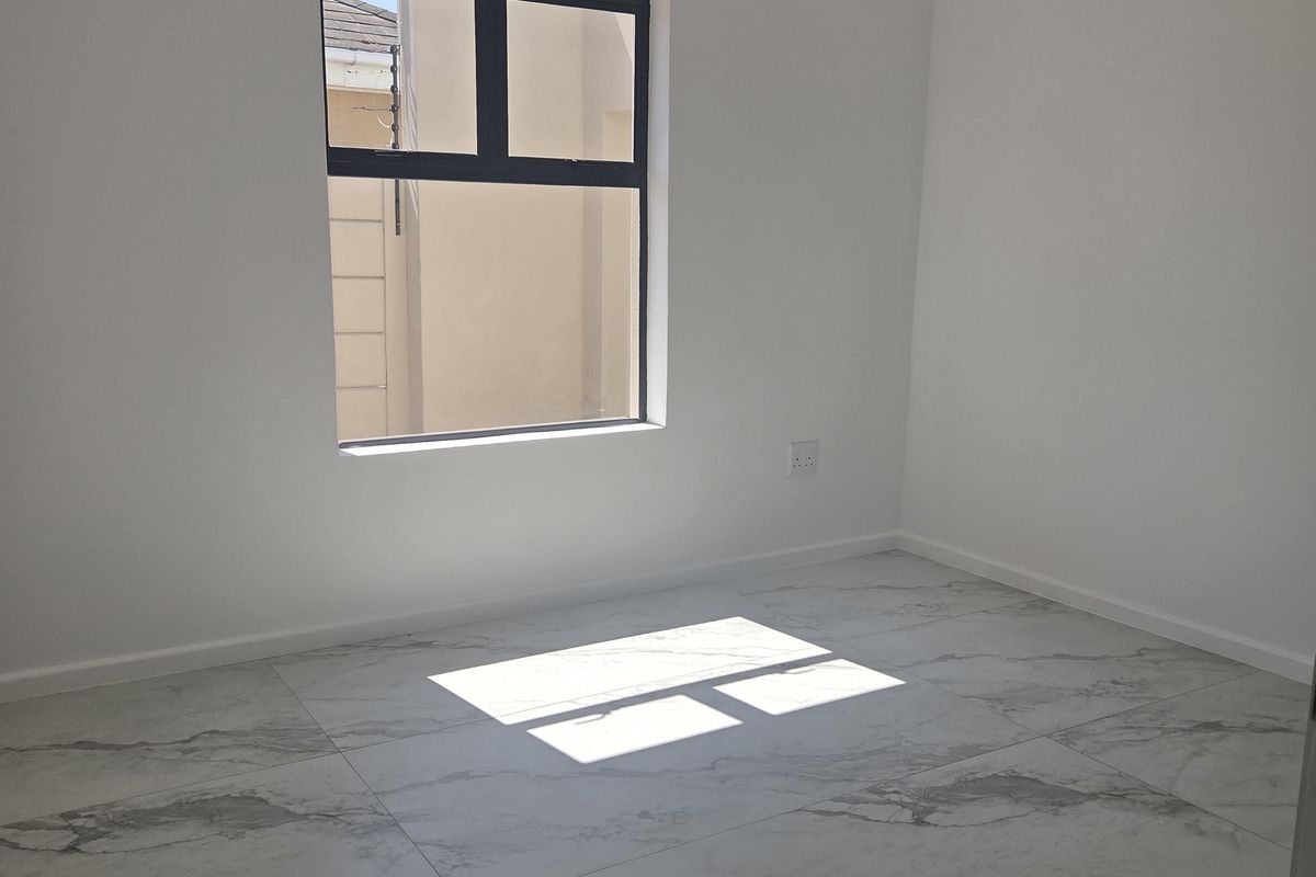 A bright, empty bedroom featuring modern marble-look porcelain floor tiles and a clean, neutral aesthetic, ready for personalization.