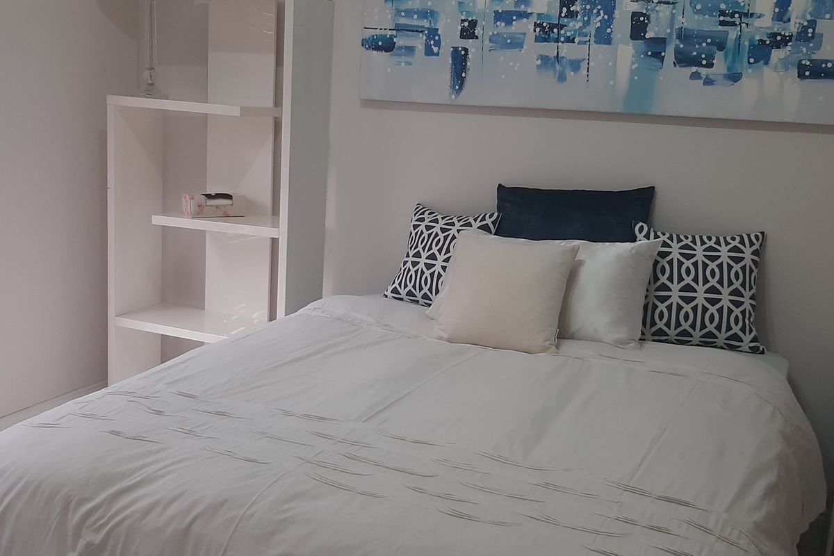 A well-maintained bedroom featuring built-in shelving and venetian blinds, providing a clean and functional living space.