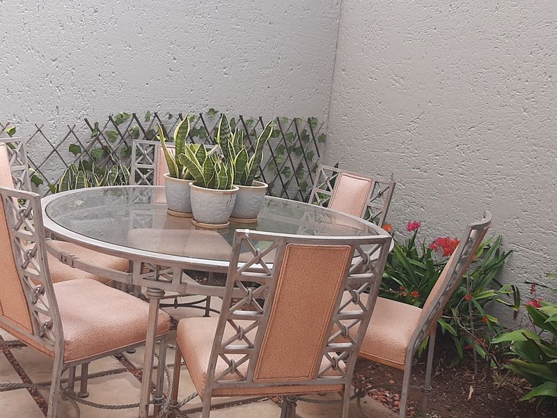 A private outdoor patio area featuring paved flooring and a high textured boundary wall, providing a secluded space for outdoor dining.