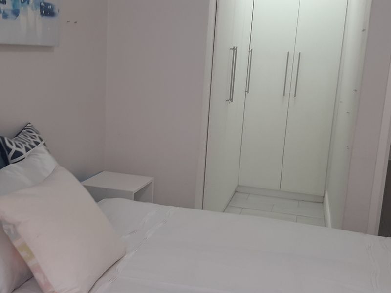 A well-maintained bedroom featuring built-in cupboards and an adjoining en-suite bathroom with a bathtub.