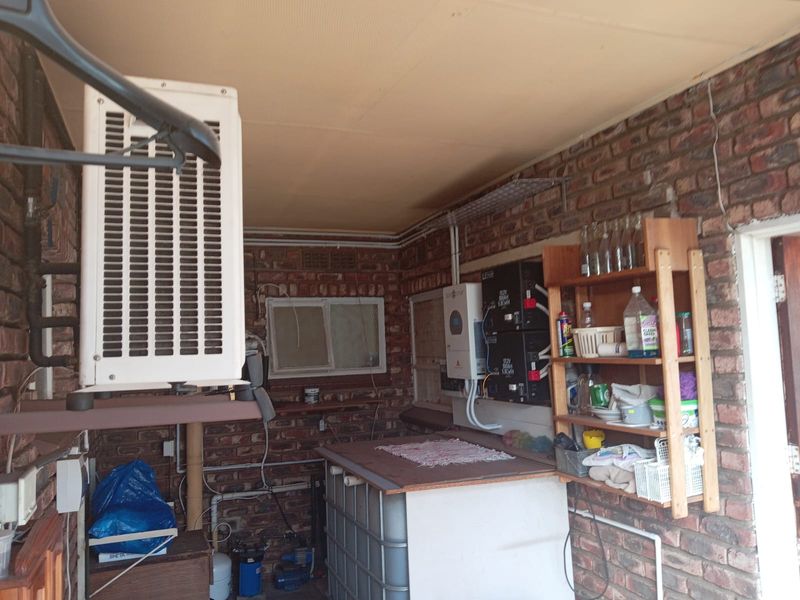 Utility area featuring exposed brick walls, housing solar power infrastructure, an air conditioning condenser unit, and a water filtration system.