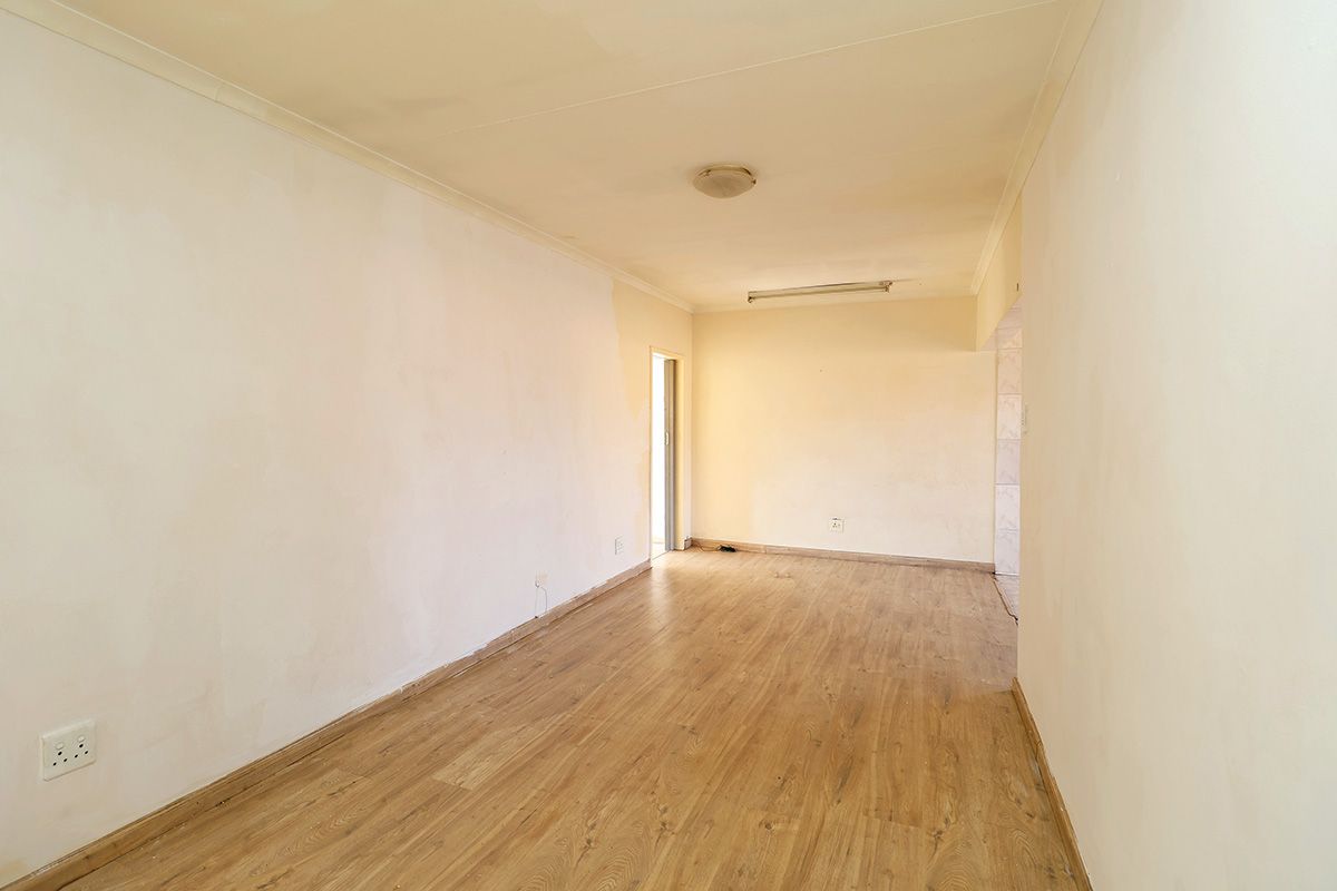 An empty, open-plan living area featuring laminate wood flooring and neutral walls, providing a blank canvas ready for personalization and interior design.