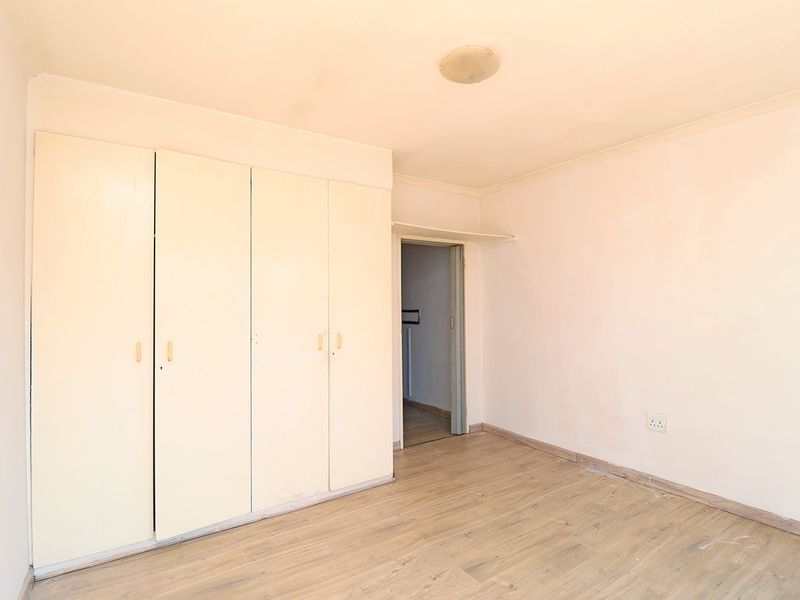 An empty bedroom featuring built-in cupboards, laminate flooring, and neutral wall finishes, offering a blank canvas for personalization.