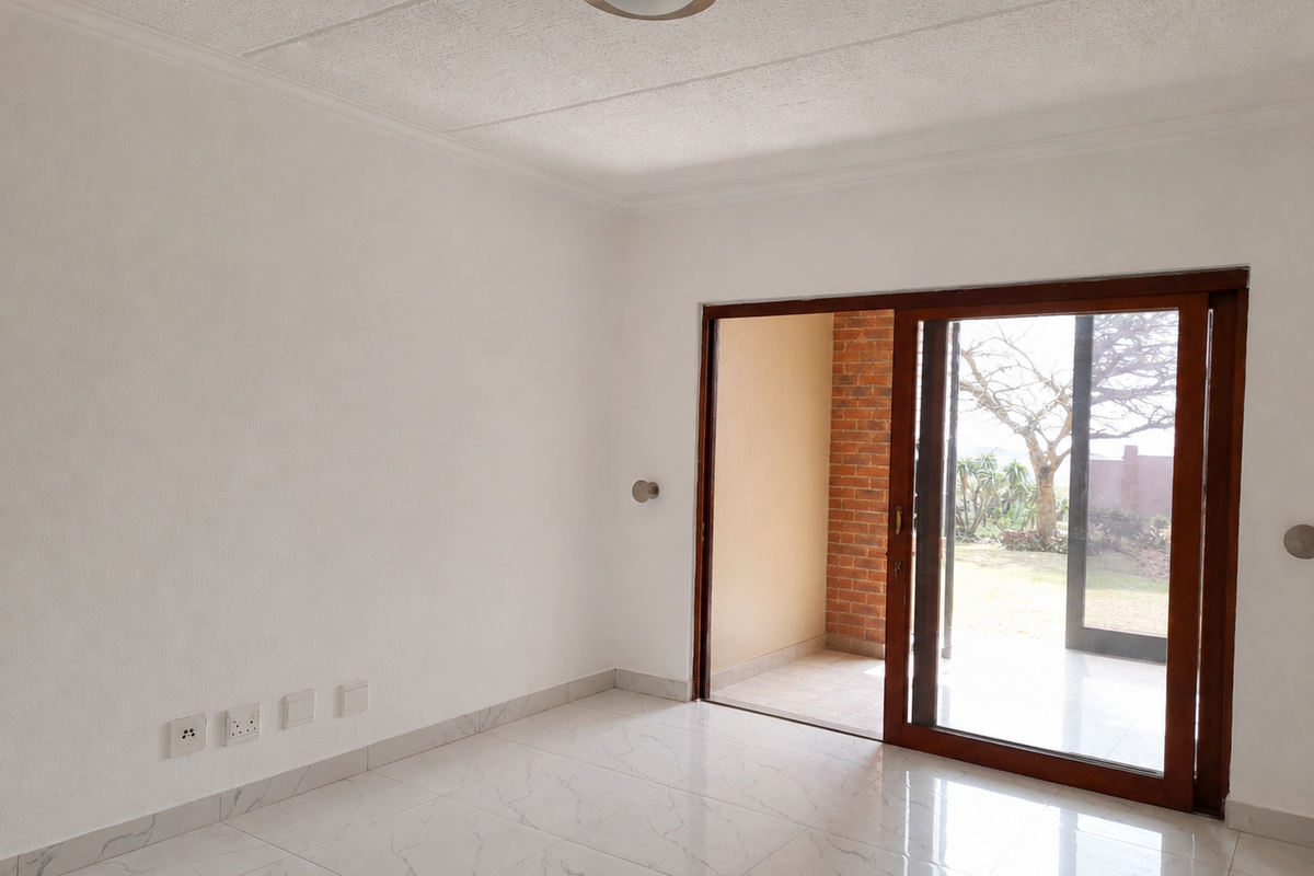 A bright, empty living room featuring white walls, marble-look tiled flooring, and a sliding glass door providing access to an outdoor patio area.