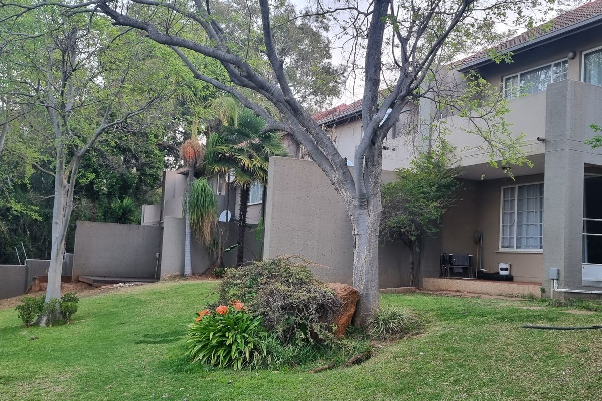 Rear view of a townhouse featuring a landscaped garden, concrete balcony, and tiled roof structure.
