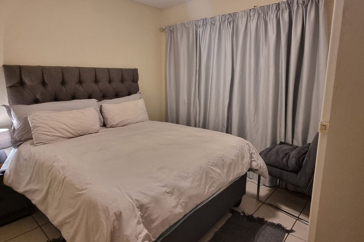 A functional bedroom featuring tiled flooring and neutral wall finishes, providing a comfortable and practical sleeping space.