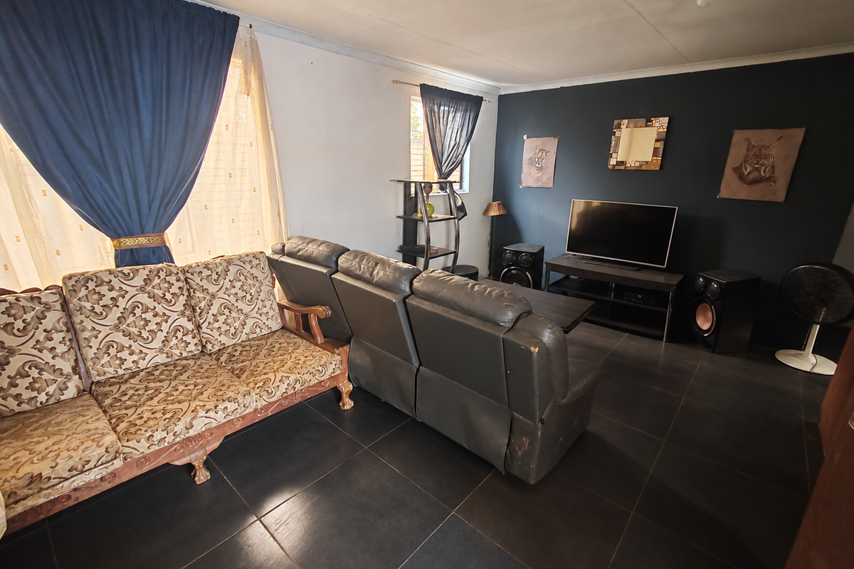 A living room featuring dark floor tiles and a contrasting accent wall, providing a functional space for relaxation.