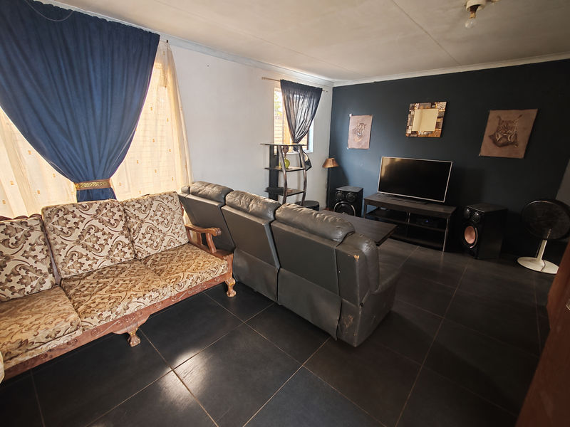 A living room featuring dark floor tiles and a contrasting accent wall, providing a functional space for relaxation.