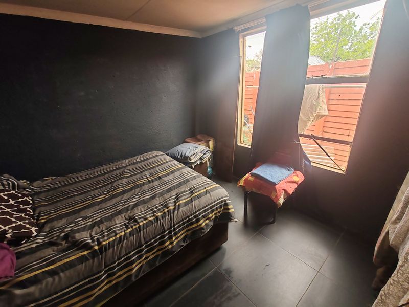 A bedroom featuring dark wall finishes and tiled flooring, with a large window providing natural light.