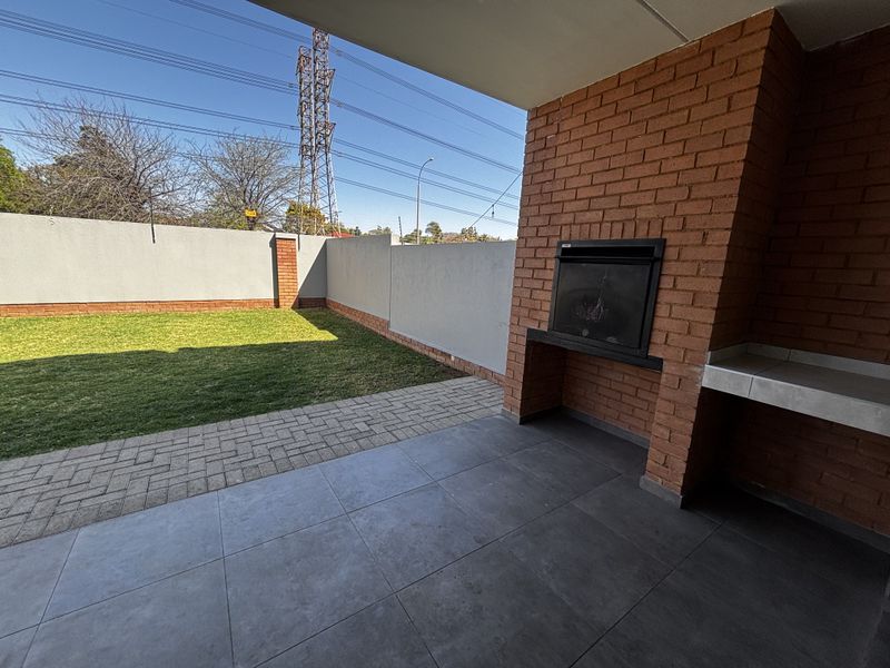 Covered patio area featuring a built-in brick braai, tiled flooring, and direct access to a private garden with paved pathways and boundary walls.