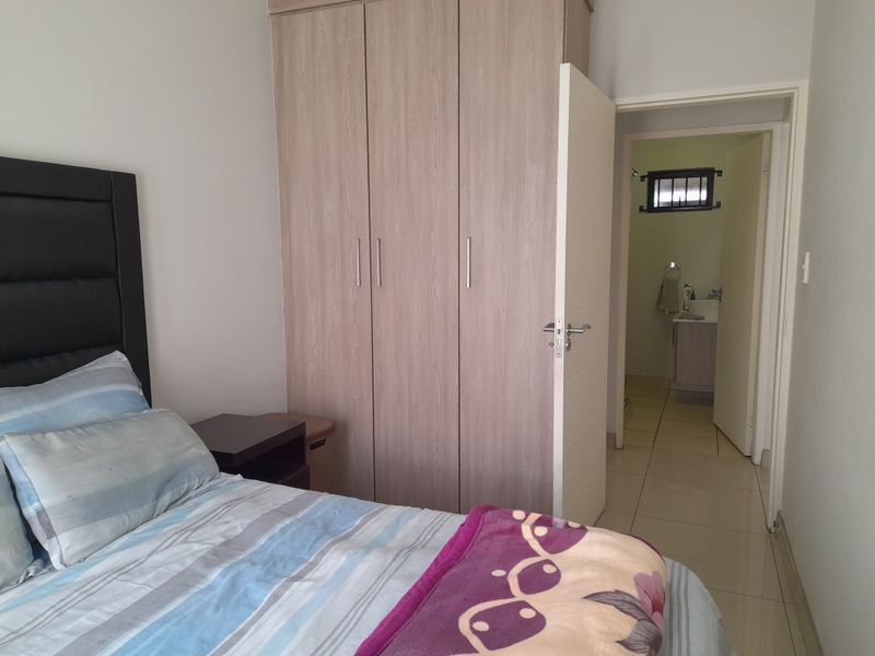 A bedroom featuring built-in wardrobes, tiled flooring, and direct access to an en-suite bathroom.
