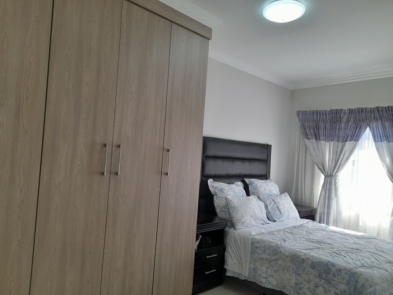 A well-maintained bedroom featuring a large built-in wardrobe with wood-grain finish and neutral wall tones.