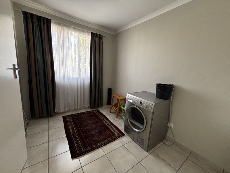 A functional laundry room featuring tiled flooring and neutral wall finishes, providing a clean and practical space for utility needs.