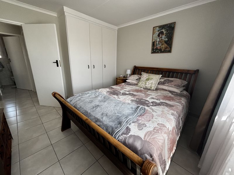 A well-maintained bedroom featuring neutral tiled flooring, built-in cupboards, and coved cornicing, offering a clean and functional living space.