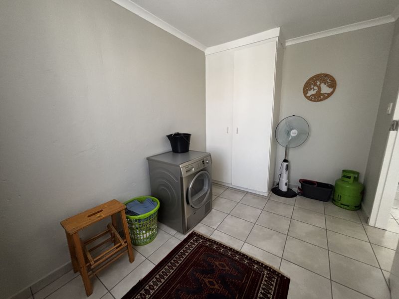 A functional laundry room featuring tiled flooring and a built-in storage cupboard, providing practical utility space for the home.