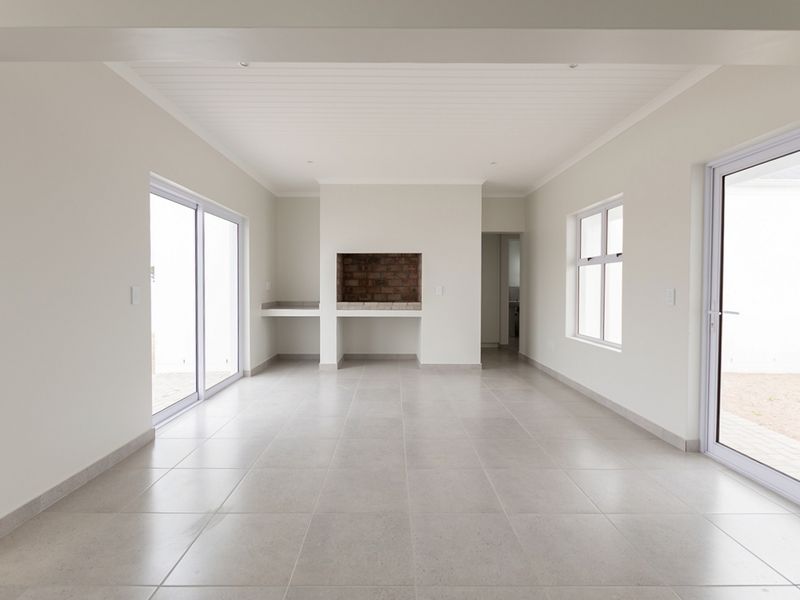 A bright, open-plan living area featuring neutral tiled floors, a built-in fireplace, and multiple sliding glass doors providing ample natural light.