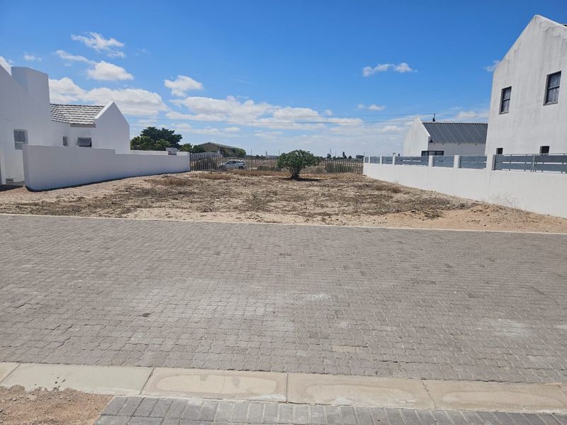 A vacant residential plot featuring a paved driveway and perimeter boundary walls, ready for development.