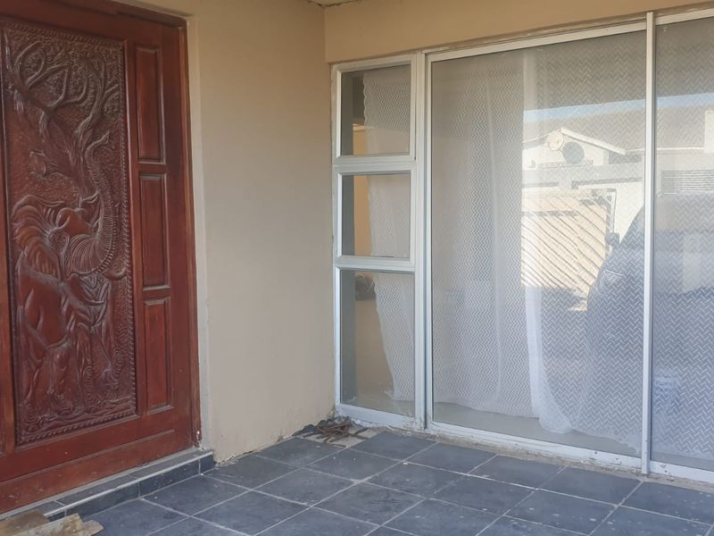 Entrance area featuring a decorative carved wooden front door and an aluminium sliding door with tiled flooring.