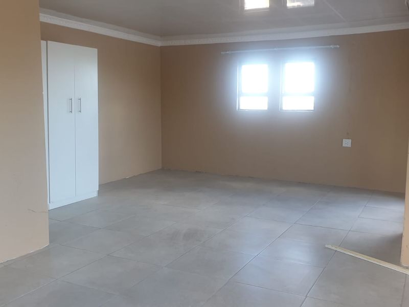 An empty bedroom featuring neutral wall paint, tiled flooring, and a built-in wardrobe, offering a blank canvas for personalization.