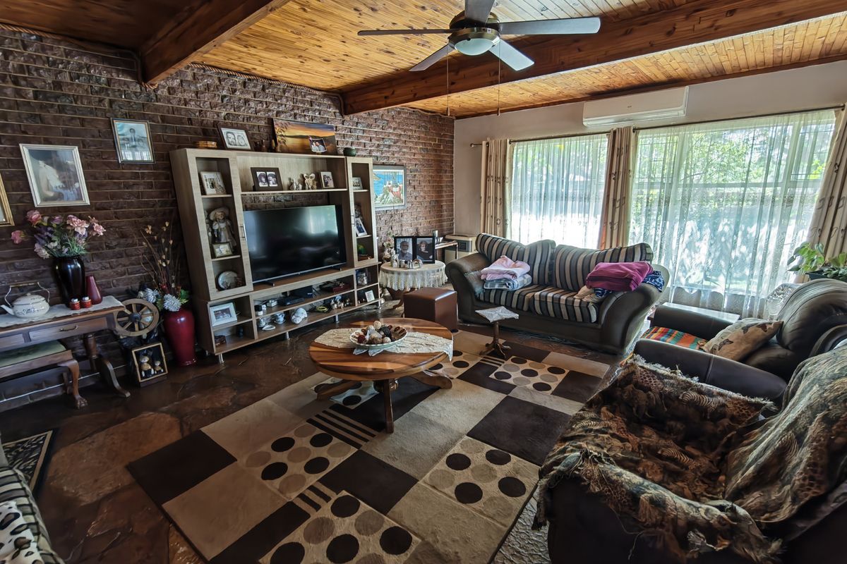 Spacious living room featuring a rustic exposed brick wall, timber-clad vaulted ceiling with exposed beams, stone flooring, and a split-system air conditioner.