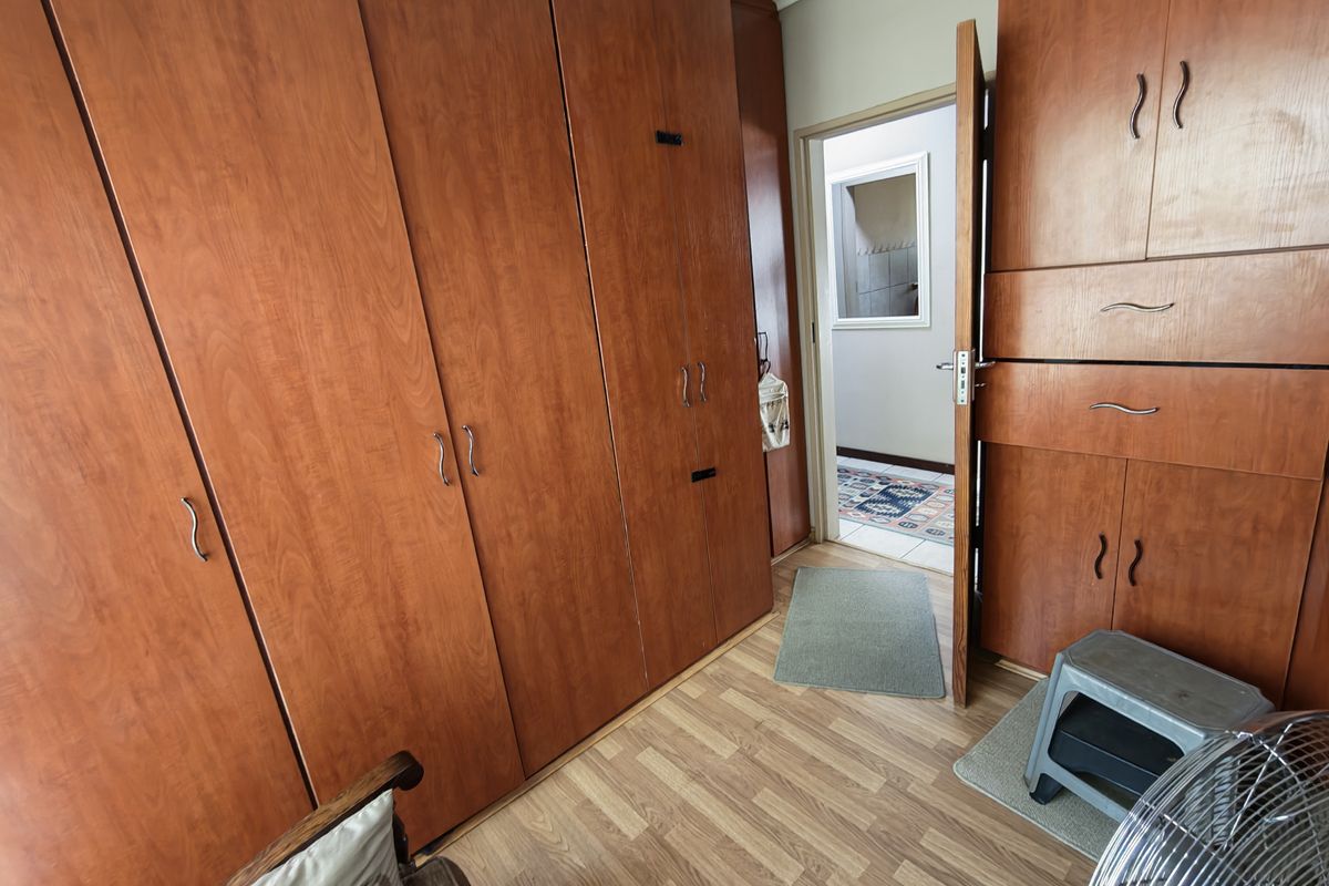 A bedroom featuring extensive built-in wooden cabinetry and laminate flooring, with a doorway leading to an adjacent hallway.