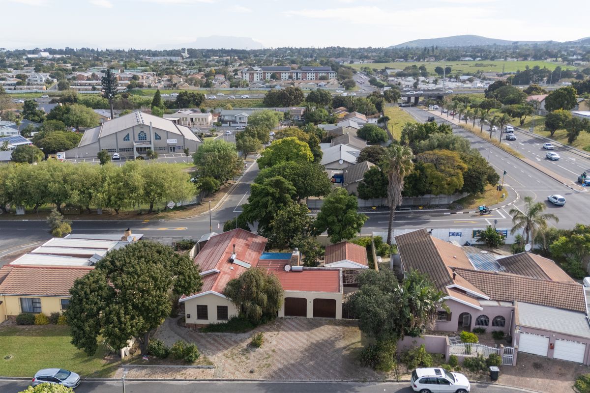 Aerial view of the property showcasing the main dwelling, double garage, paved driveway, and private swimming pool within the suburban neighborhood setting.