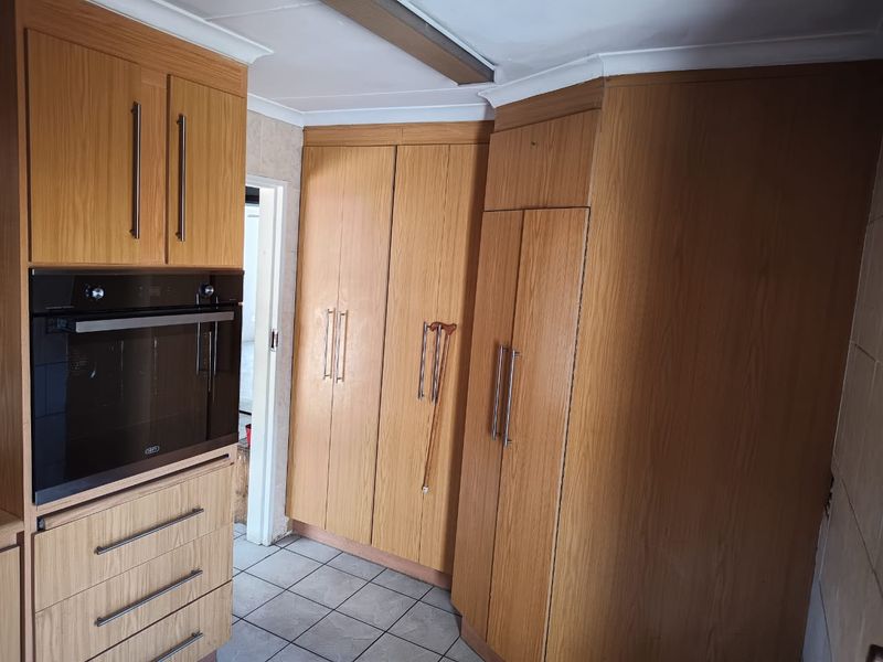 A functional kitchen area featuring built-in wooden cabinetry, an integrated oven, and tiled flooring, offering a solid foundation for a modern renovation.