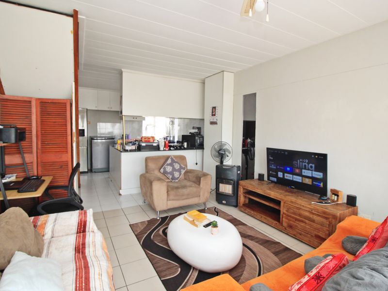 Open plan living area featuring tiled flooring and an integrated kitchen space with built-in cabinetry and countertops.