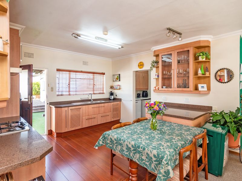 A functional kitchen featuring wood-finish cabinetry, laminate countertops, a gas hob, and a dedicated dining area with direct access to the exterior.
