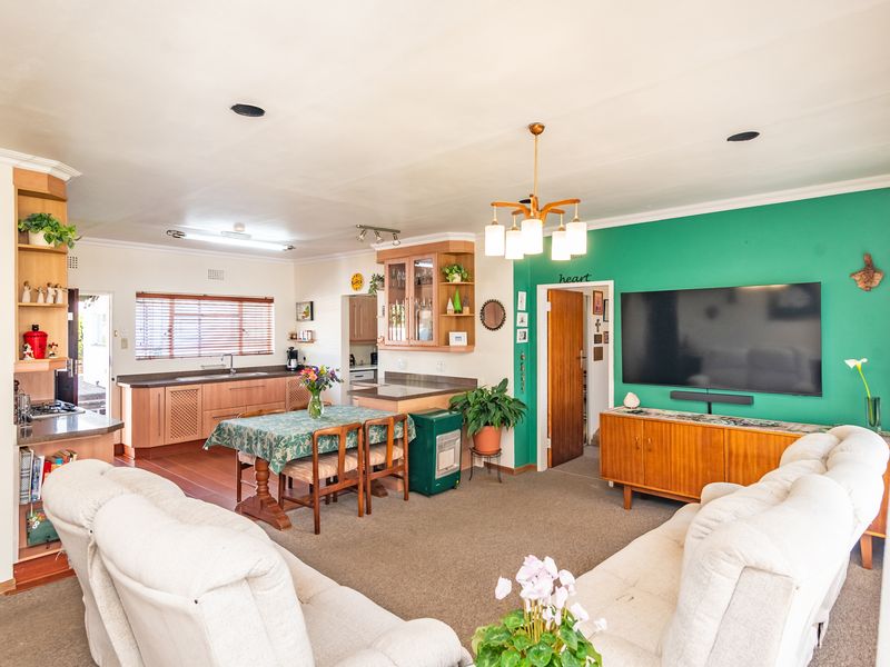 Open-plan living and kitchen area featuring built-in cabinetry, laminate countertops, and a bright green accent wall, creating a functional and connected living space.