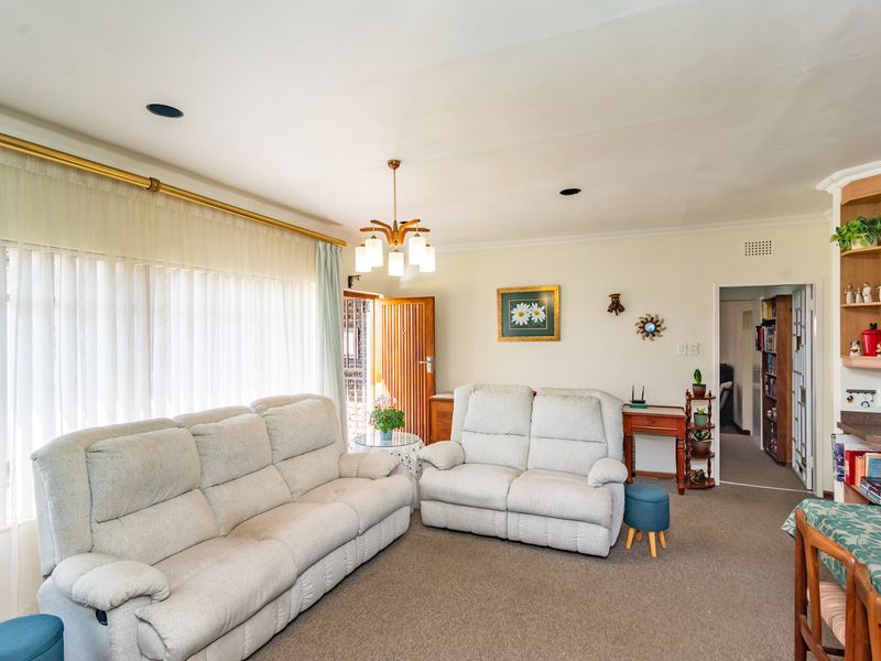 A comfortable living room featuring carpeted flooring, recessed lighting, and a built-in shelving unit, offering a functional and well-lit space.
