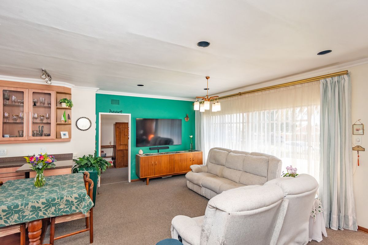 A spacious living room featuring built-in cabinetry, recessed lighting, and large windows with floor-to-ceiling curtains, offering a comfortable and functional living space.