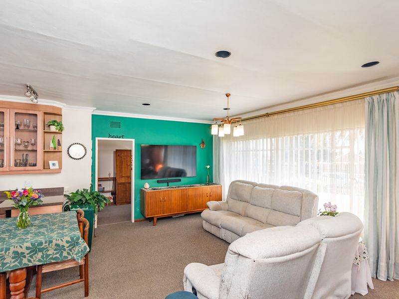 A spacious living room featuring built-in cabinetry, recessed lighting, and large windows with floor-to-ceiling curtains, offering a comfortable and functional living space.