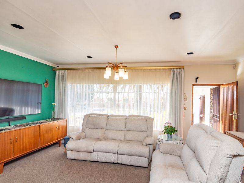 A comfortable living room featuring recessed lighting, coved ceilings, and large windows that provide ample natural light.
