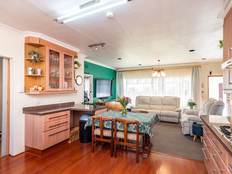 Open-plan living and kitchen area featuring laminate flooring, built-in cabinetry, stone countertops, and a gas hob, creating a functional and connected living space.
