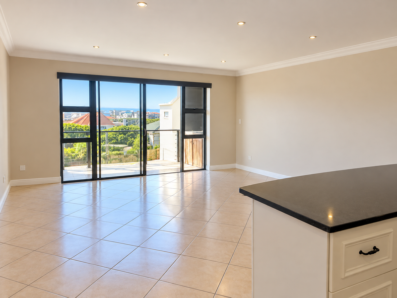 Spacious open-plan living area featuring neutral ceramic tiling, recessed lighting, and large sliding doors leading to a balcony with scenic views.