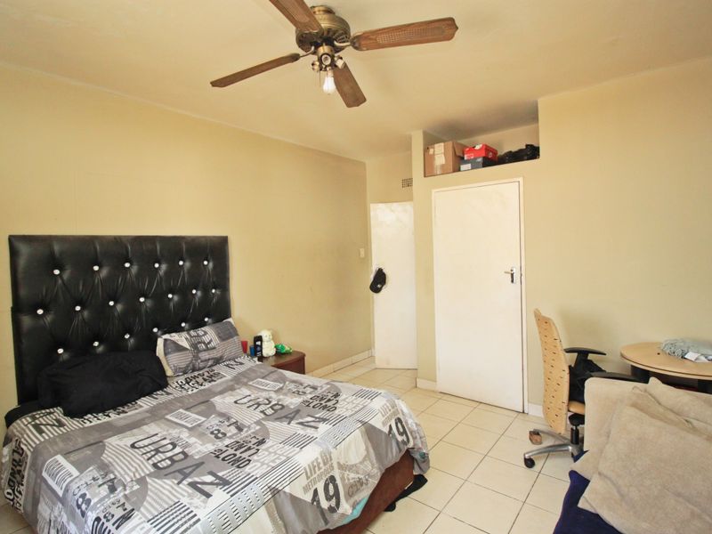 A bedroom featuring tiled flooring, a ceiling fan, and a built-in storage niche above the doorway.
